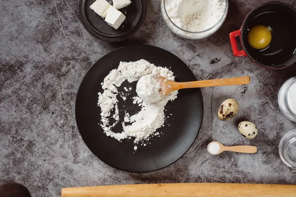 Ingredients and utensils for baking. Spoon with flour, dishes, eggs,  butter salt and rolling pin on a grey background. Flat lay. Text space