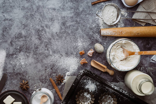 Здоровые пищевые ингредиенты. Ложка с мукой, посуда, яйца, соль масла и скалка на сером фоне. Вид сверху, пространство для копирования
.