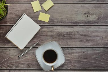 Ahşap ofis resepsiyon masası ile bir dizüstü bilgisayar, bir kolu, bir fincan kahve ve bir saksıyı. Kopya alanı ile üstten görünüm.