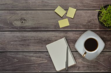 Ahşap ofis resepsiyon masası ile bir dizüstü bilgisayar, bir kolu, bir fincan kahve ve bir saksıyı. Kopya alanı ile üstten görünüm.