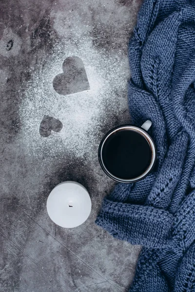 Cup of coffee , candle and warm woolen sweater  on gray table.Winter concept. Flat lay, top view. Valentines day.