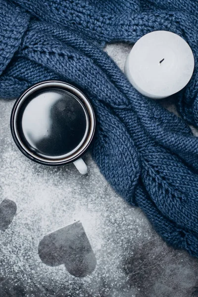 Cup of coffee , candle and warm woolen sweater  on gray table.Winter concept. Flat lay, top view. Valentines day.