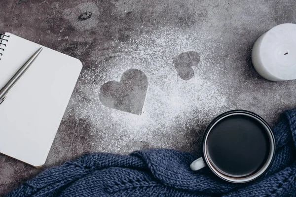 Cup of coffee , candle, notebook, pen and warm woolen sweater  on gray table.Winter concept. Flat lay, top view. Valentines day.