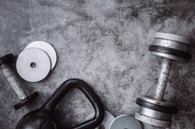 Fitness veya vücut geliştirme kavramı arka plan. Eski demir dumbell ve spor salonunda gri, beton zemin üzerinde Kettlebell. Üstten görünüm. Healthz yaşam tarzı.