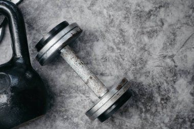 Fitness veya vücut geliştirme kavramı arka plan. Eski demir dumbell ve spor salonunda gri, beton zemin üzerinde Kettlebell. Üstten görünüm. Healthz yaşam tarzı.