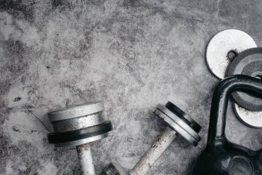 Fitness veya vücut geliştirme kavramı arka plan. Eski demir dumbell ve spor salonunda gri, beton zemin üzerinde Kettlebell. Üstten görünüm. Healthz yaşam tarzı.