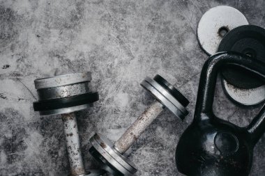 Fitness veya vücut geliştirme kavramı arka plan. Eski demir dumbell ve spor salonunda gri, beton zemin üzerinde Kettlebell. Üstten görünüm. Healthz yaşam tarzı.