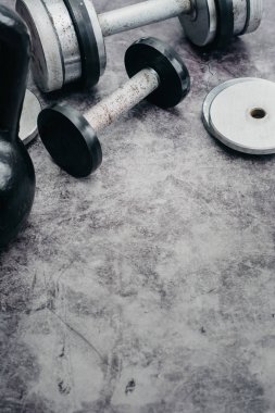 Fitness veya vücut geliştirme kavramı arka plan. Eski demir dumbell ve spor salonunda gri, beton zemin üzerinde Kettlebell. Üstten görünüm. Healthz yaşam tarzı.