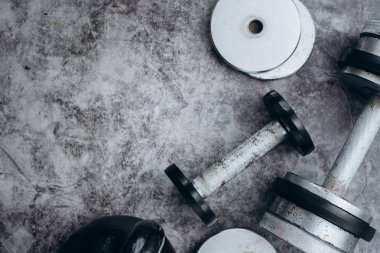 Fitness veya vücut geliştirme kavramı arka plan. Eski demir dumbell ve spor salonunda gri, beton zemin üzerinde Kettlebell. Üstten görünüm. Healthz yaşam tarzı.