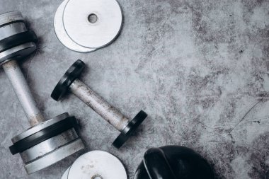 Fitness veya vücut geliştirme kavramı arka plan. Eski demir dumbell ve spor salonunda gri, beton zemin üzerinde Kettlebell. Üstten görünüm. Healthz yaşam tarzı.