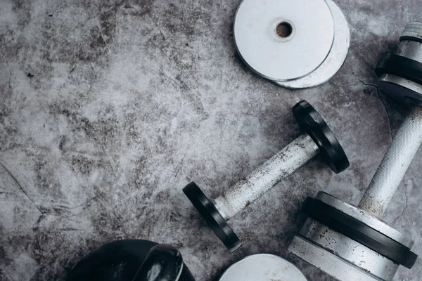 Fitness veya vücut geliştirme kavramı arka plan. Eski demir dumbell ve spor salonunda gri, beton zemin üzerinde Kettlebell. Üstten görünüm. Healthz yaşam tarzı.