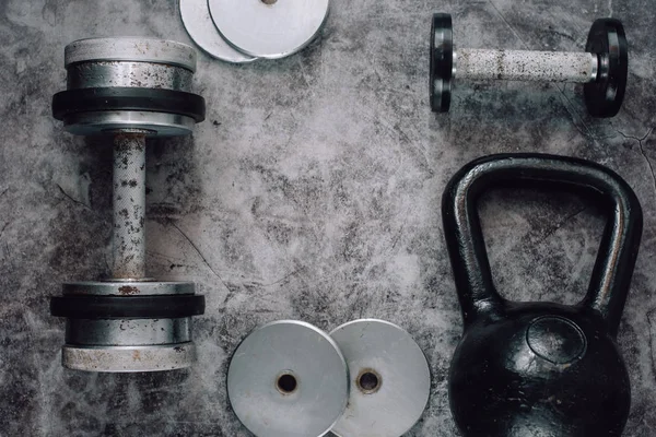 Fitness or bodybuilding concept background. Old iron dumbbells and Kettlebell on grey, conrete floor in the gym.  Top view. Healthz lifestyle.