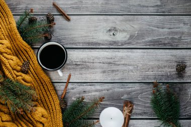Bir fincan kahve, mum, darbe, tarçın, çam dalları ve ahşap masa üzerinde sıcak turuncu eşarp. Kış konsepti. Düz yatıyordu, en iyi görünümü. 