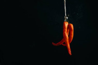 Grup, karanlık bir arka plan üzerinde yazıt tarafından bağlı kırmızı sıcak biber chilies biber. Metin için yer