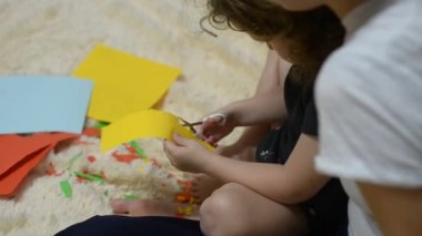 Anne çocuğunu renkli kağıt kesmek için yardım.