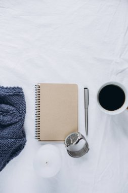 Fincan kahve, mavi örgü kazak, defter kalem, saat, mum ile yatak, en iyi görünüm. Kadın giyim. Düz yatıyordu, rahat kavramı