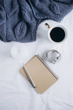 Fincan kahve, mavi örgü kazak, defter kalem, saat, mum ile yatak, en iyi görünüm. Kadın giyim. Düz yatıyordu, rahat kavramı