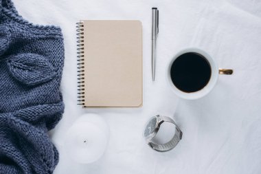 Fincan kahve, mavi örgü kazak, defter kalem, saat, mum ile yatak, en iyi görünüm. Kadın giyim. Düz yatıyordu, rahat kavramı