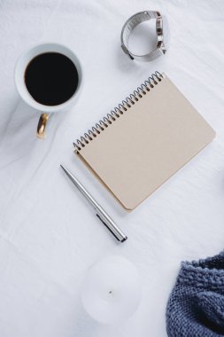 Fincan kahve, mavi örgü kazak, defter kalem, saat, mum ile yatak, en iyi görünüm. Kadın giyim. Düz yatıyordu, rahat kavramı