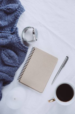 Fincan kahve, mavi örgü kazak, defter kalem, saat, mum ile yatak, en iyi görünüm. Kadın giyim. Düz yatıyordu, rahat kavramı