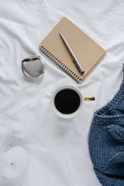 Fincan kahve, mavi örgü kazak, defter kalem, saat, mum ile yatak, en iyi görünüm. Kadın giyim. Düz yatıyordu, rahat kavramı
