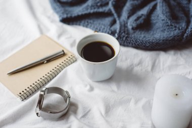 Fincan kahve, mavi örgü kazak, defter kalem, saat, mum ile yatak, en iyi görünüm. Kadın giyim. Düz yatıyordu, rahat kavramı