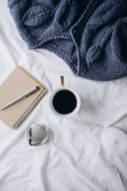 Fincan kahve, mavi örgü kazak, defter kalem, saat, mum ile yatak, en iyi görünüm. Kadın giyim. Düz yatıyordu, rahat kavramı