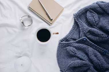Fincan kahve, mavi örgü kazak, defter kalem, saat, mum ile yatak, en iyi görünüm. Kadın giyim. Düz yatıyordu, rahat kavramı