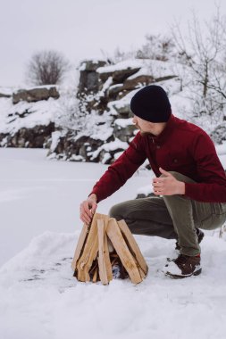 Genç adam odun odun kış döneminde yakınındaki donmuş gölün. Aktif tatiller spor hiking açık macera 