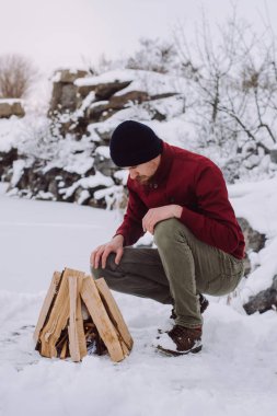 Genç adam odun odun kış döneminde yakınındaki donmuş gölün. Aktif tatiller spor hiking açık macera 