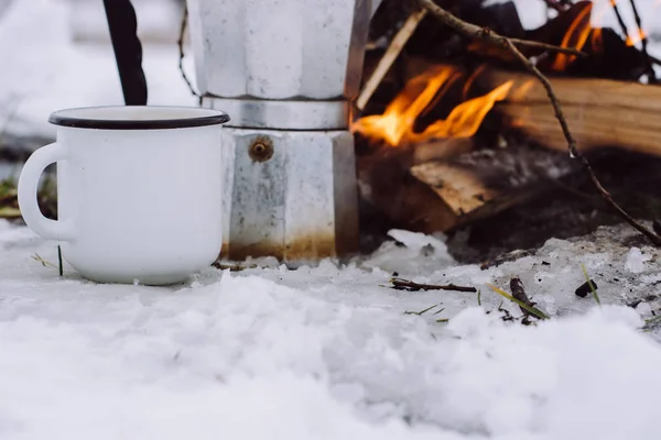 up of coffee and a coffee maker on the background Camp fire an in winter time, surrounded by snow against the near of the frozen lake. Concept adventure active vacations outdoor hiking sport