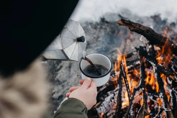 旅行妇女坐在营火附近在冬天时间和倒自己热咖啡 概念冒险活跃假期户外 冬季露营 — 图库照片