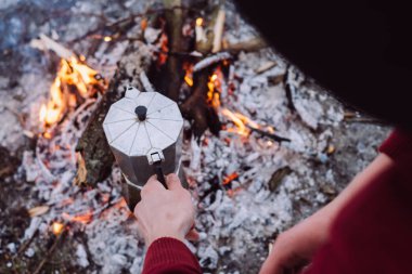 Kış tatili. Turist şapkalı kış zamanında kamp ateşi üzerine kahve pişirmek. Kavramı macera aktif tatiller açık. 
