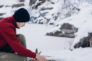 Kış Kampı. Adam sıcak eller bir yangın ve aşçı kahve yakınındaki oteller donmuş gölün. Kavramı macera aktif tatiller açık. 