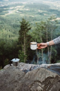 Kızlar el doğa arka plan üzerinde kamp ateşi yanında kahve bir fincan sıcak tutar. Kavramı macera aktif tatiller açık. Yaz Kampı.