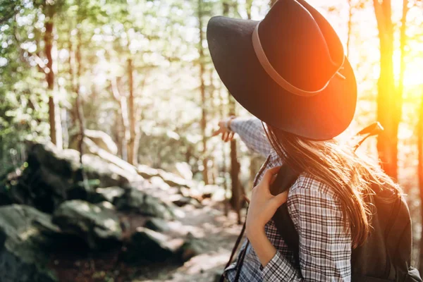 Woman in hat looking forward at amazing forest an in sunset time.  Concept adventure active vacations outdoor, space for text, atmospheric epic moment