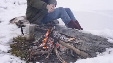Şapkalı kız ellerini yangın yanında kışın sıcak. Kavramı macera aktif tatiller açık. Kış kamp