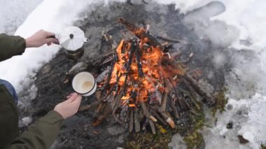Seyahat-kadın oturur camp yakınındaki bir ateş içinde bir kış zaman ve kendisi sıcak kahve dökülen. Kavramı macera aktif tatiller açık. Kış kamp