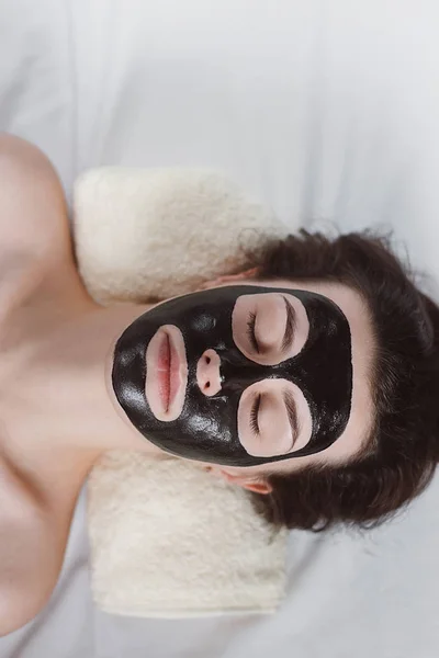 目を持つ美しい少女は 彼女の顔に黒いマスクを応用でリラックス閉鎖 彼女の顔に黒いマスクを浄化と女性 皮膚のケアと美容のコンセプト — ストック写真
