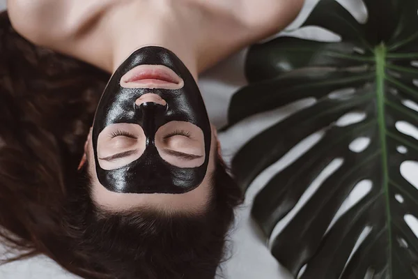매력적인 여자와 편안한 침대에 스파를 즐기고 그녀의 얼굴에 마스크를 — 스톡 사진