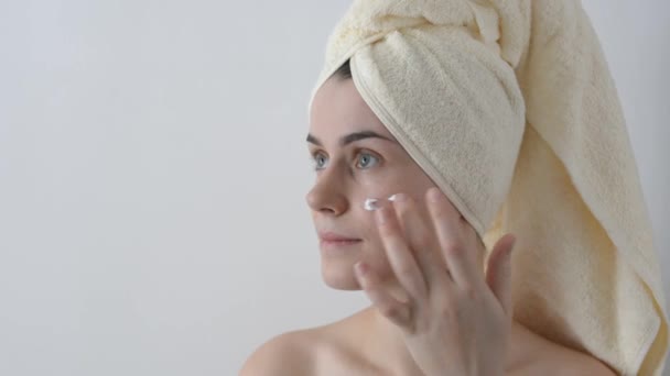 魅力的な若い女の子 バスタオルで包まれた後 シャワーを彼女の顔にクリームを適用します 皮膚のケアと美容のコンセプト — ストック動画