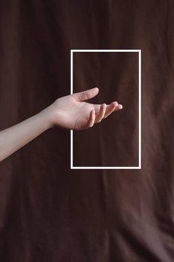 El çekilmiş beyaz bir çerçeve ile kahverengi kumaş arka plan üzerinde. En az yaratıcı soyut kavram. Düz yatıyordu. Metin için yer kopyalayın