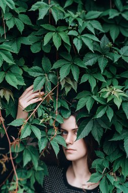 Güzel genç kadın, yeşil bir arka plana dayanır portre yaz aylarında açık bırakır. Yeşil yaprakları doğanın keyfini kız