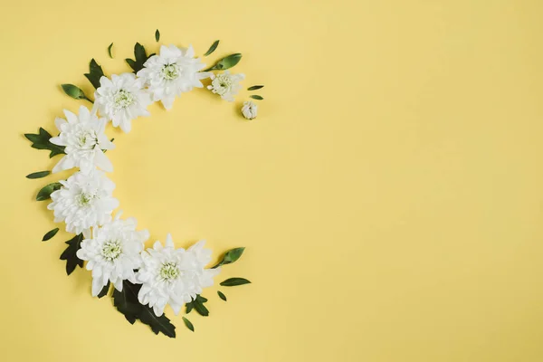 Creative flowers composition. Wreath made of white flowers on yellow background. Mothers day, womens day, spring concept. Flat lay, top view, copy space