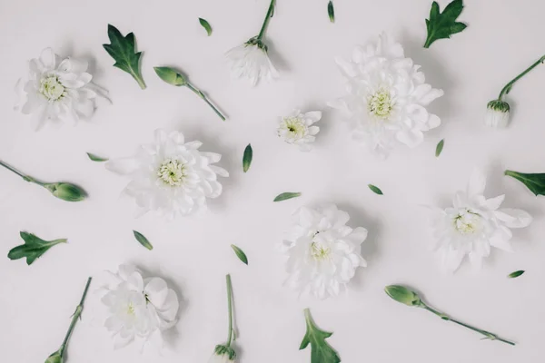 Beautiful floral pattern made of white floral, green leaves, branches on white background. Flat lay, top view. Spring background.