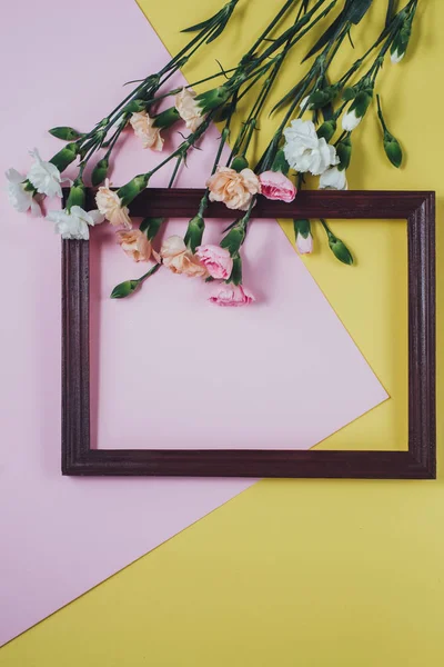 Composizione creativa con fiori primaverili. Fiori bianchi e cornice in legno su sfondo rosa pastello e giallo. Layout piatto, vista dall'alto, spazio di copia — Foto Stock