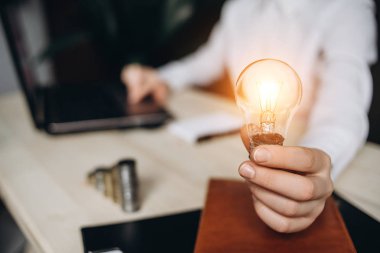 Bir ofis ve Sandra'ya işkence yapmak bilgisayar masasında ampulleri tutan iş kadın. Muhasebe Finans ve enerji tasarrufu fikir