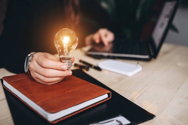 Bir ofis ve inşaat üstünde bilgisayar masasında ampulleri tutan iş kadın. Yenilik ve yaratıcılık kavramı ekip çalışması fikir