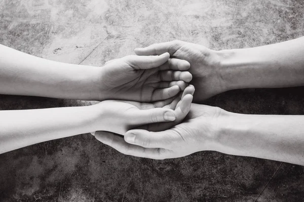 Νεαρή οικογένεια κρατώντας τα χέρια προσφέροντας βοήθεια, προστασία και υποστήριξη σύμβολο. Κοινή χρήση έννοια ελπίδα — Φωτογραφία Αρχείου