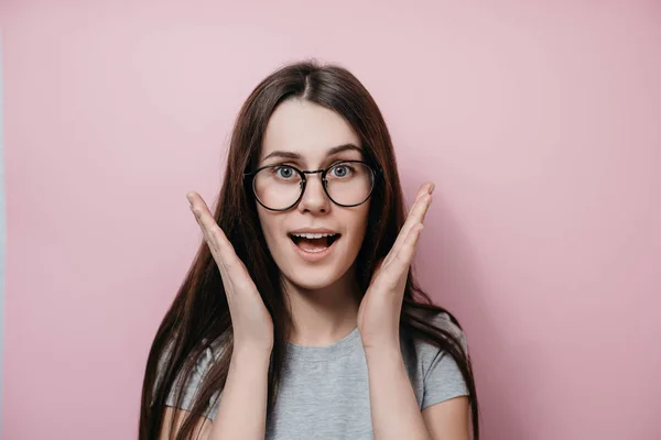 Sorpresa felice giovane femmina in occhiali con la bocca spalancata occhi gesticolando con palme vicino al viso isolato su sfondo giallo. Emozioni positive, espressioni facciali, linguaggio del corpo — Foto Stock